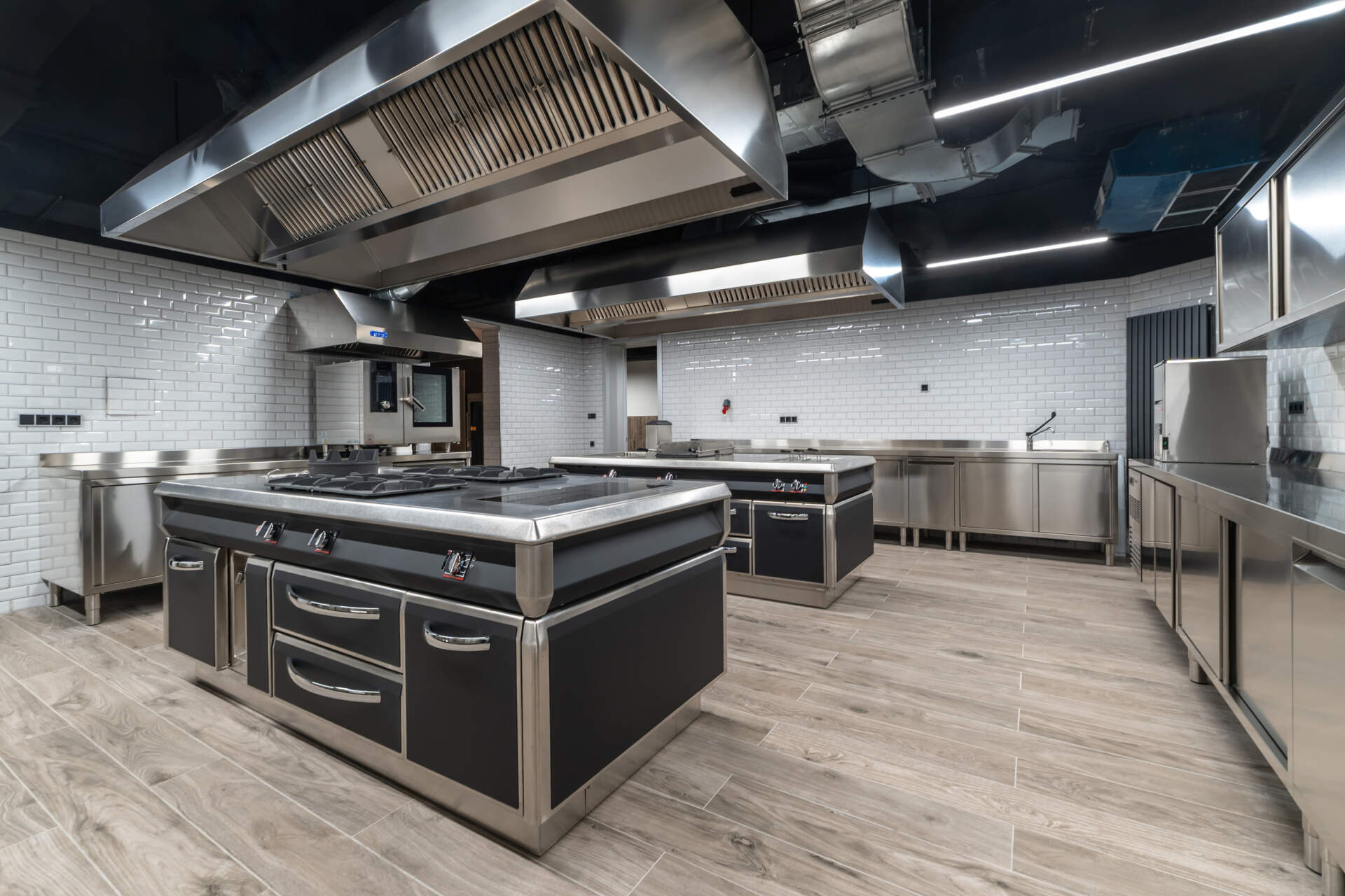 A well-equipped commercial kitchen features extensive stainless steel surfaces, efficient cooking appliances, and a clean, organized layout, perfect for culinary activities